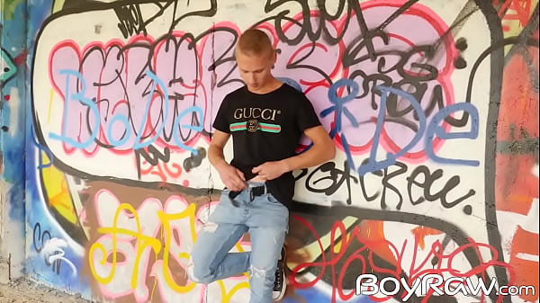 Young guy masturbates in public in front of graffiti wall